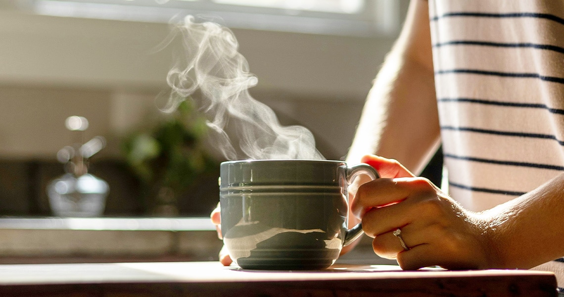 Una mujer con una taza de café caliente en la mano