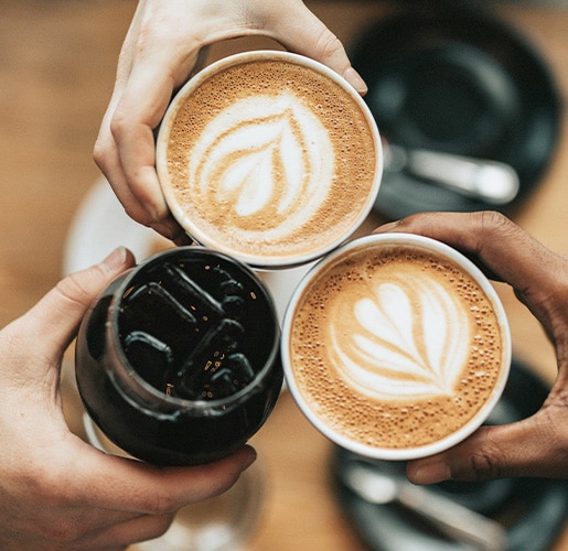 three people holding coffee drinks