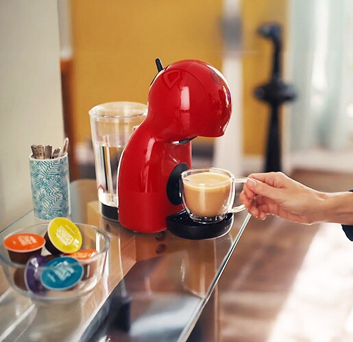 person grabbing a coffee prepared with a dolce gusto coffee machine