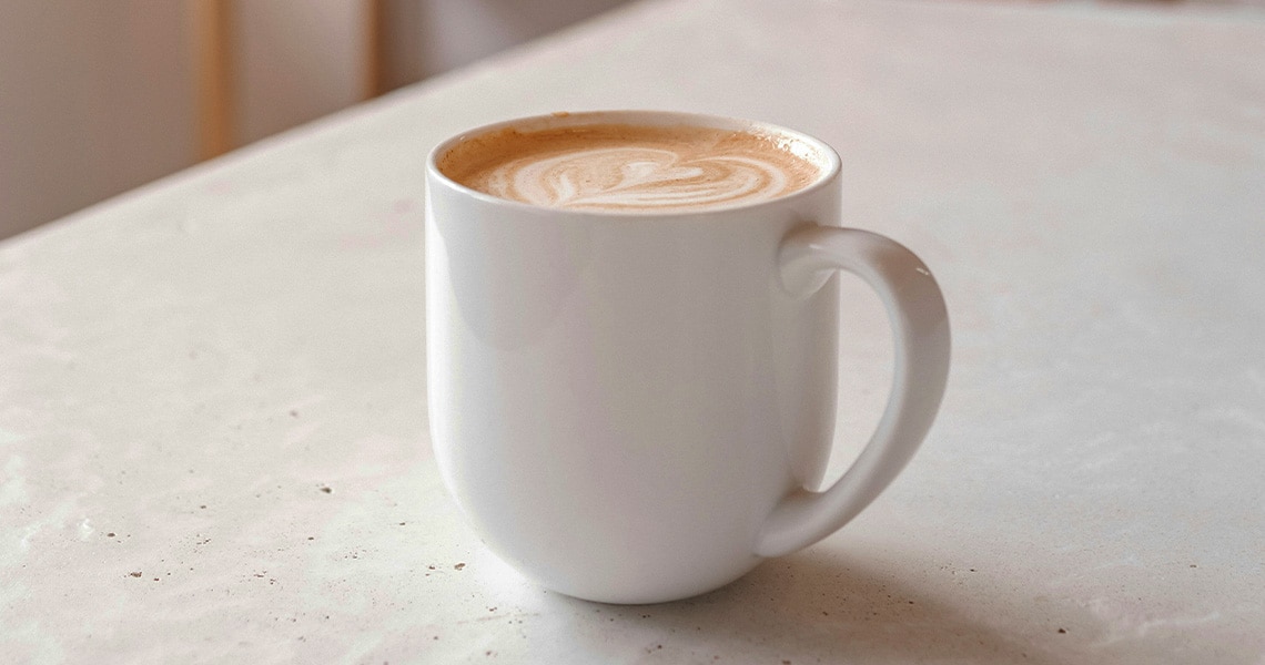 Una mujer con una taza de café con leche en la mano